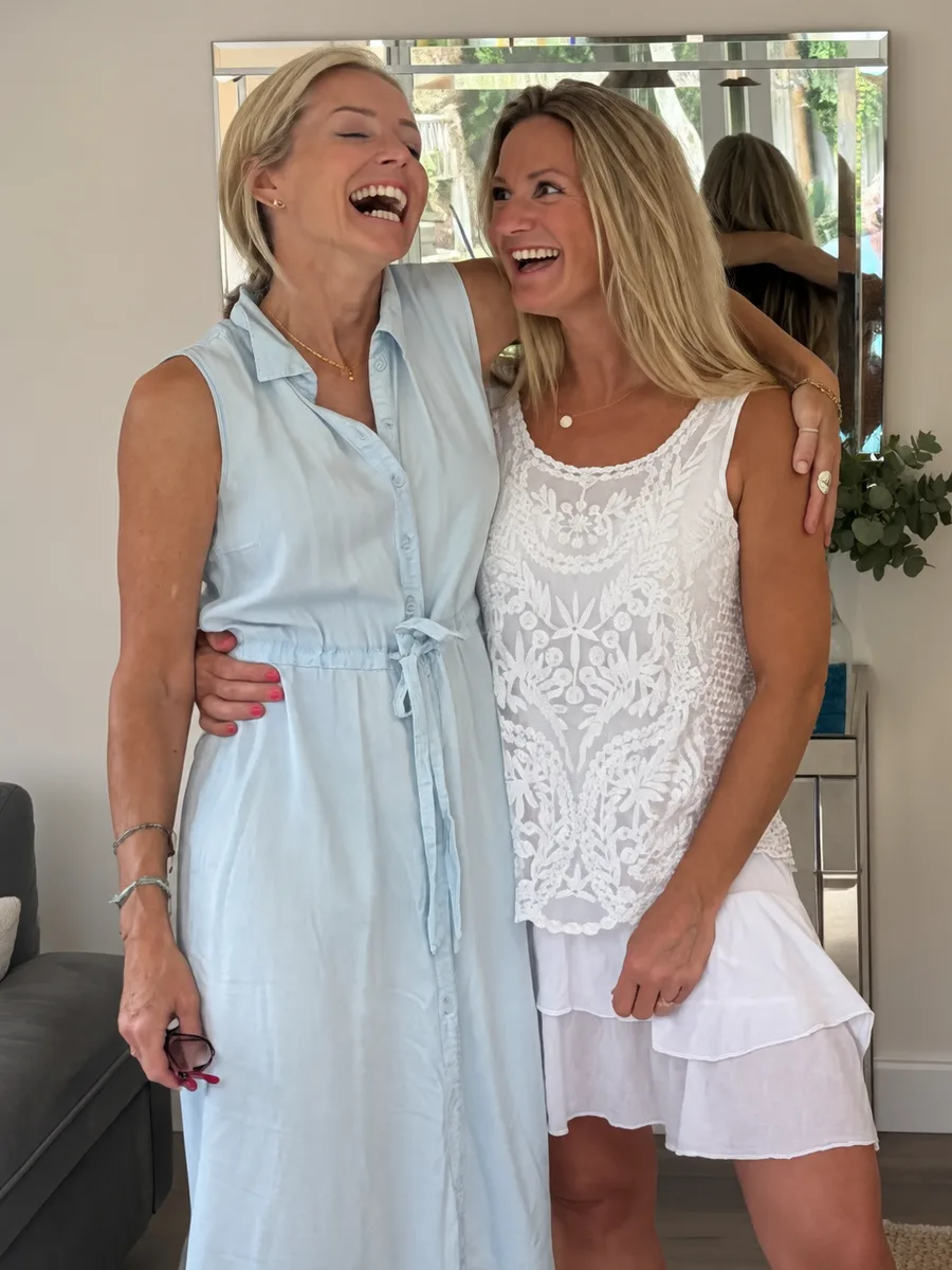 Two friends laughing with their arms around each other in the studio
