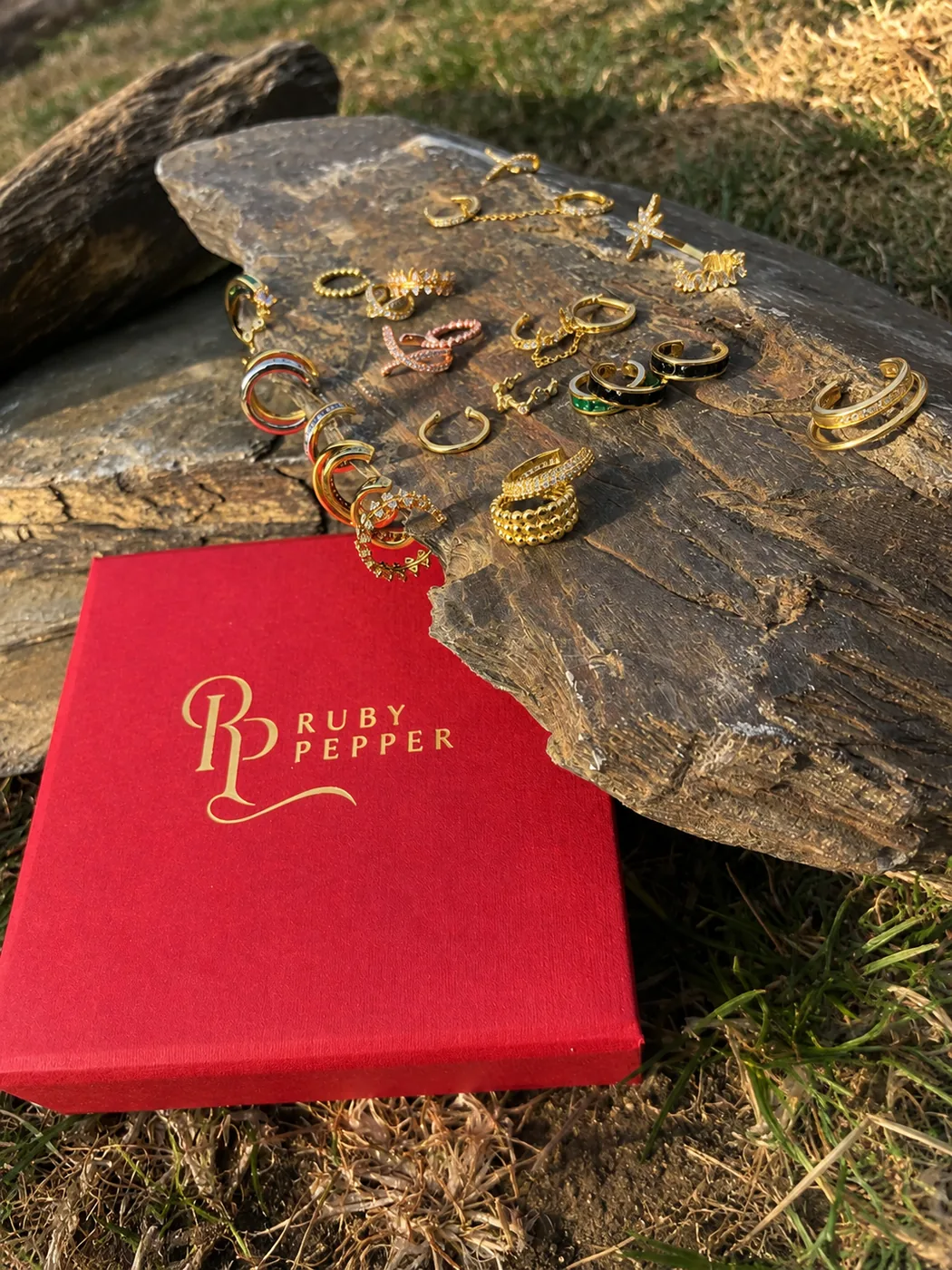 Open ruby leather jewellery keepsake box with cream velvet interior holding fine gold rings and earrings