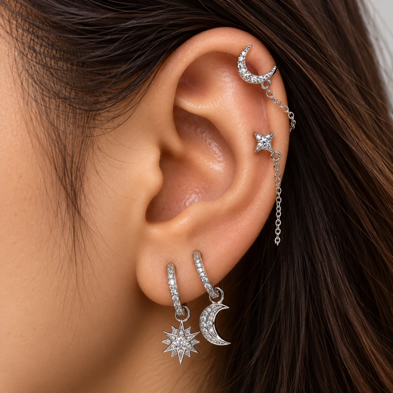Crystal moon and star chain earrings with pavé huggies carrying a starburst and a crescent moon charm