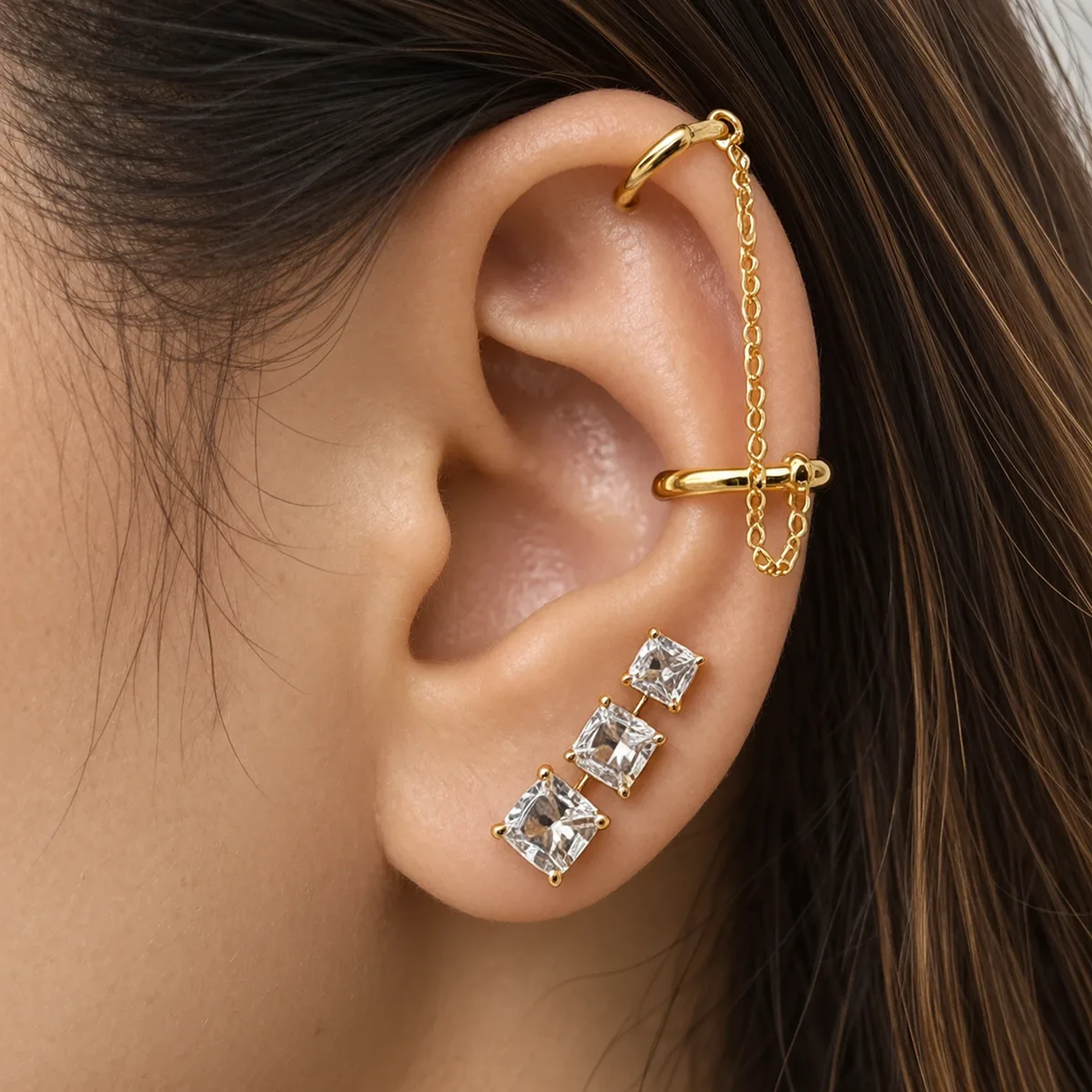 Gold chain-linked ear cuffs with graduated princess-cut crystal studs
